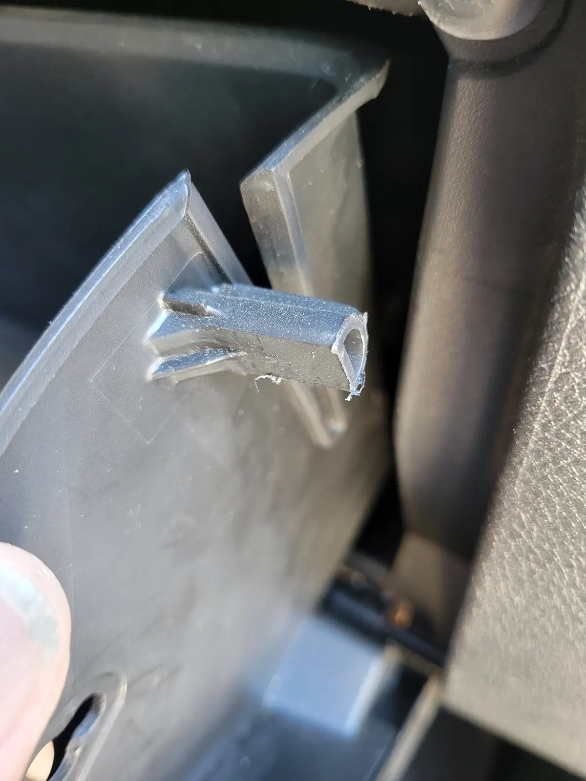 close view of one of two tabs on a side of the vehicle glove box