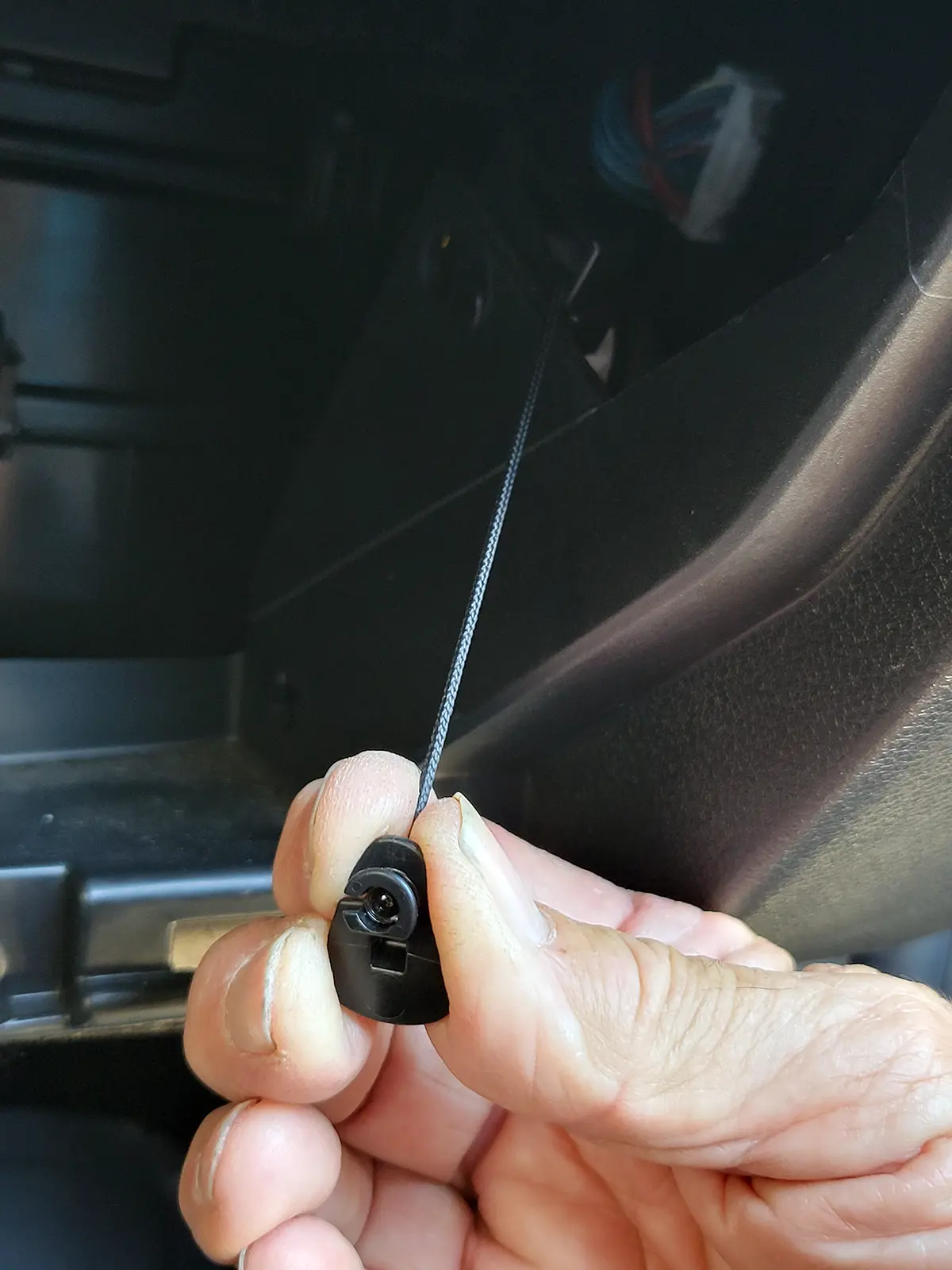 a hand holds the spring-loaded cable to put the glove box back in place