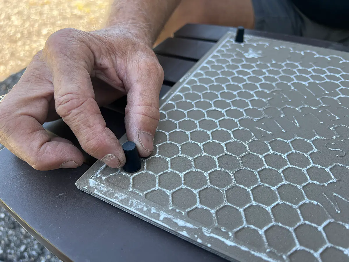 close view of a hand holding a stopper in place on the bottom of an floor tile