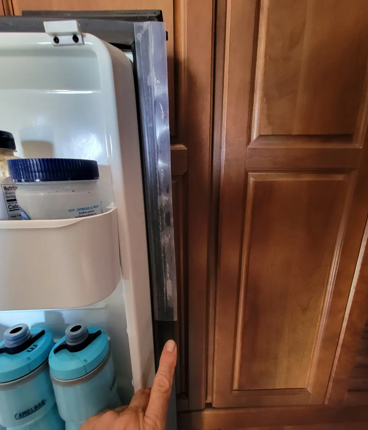 view of a larger section of silicone seal tape previously applied to the upper portion of the refrigerator door gasket