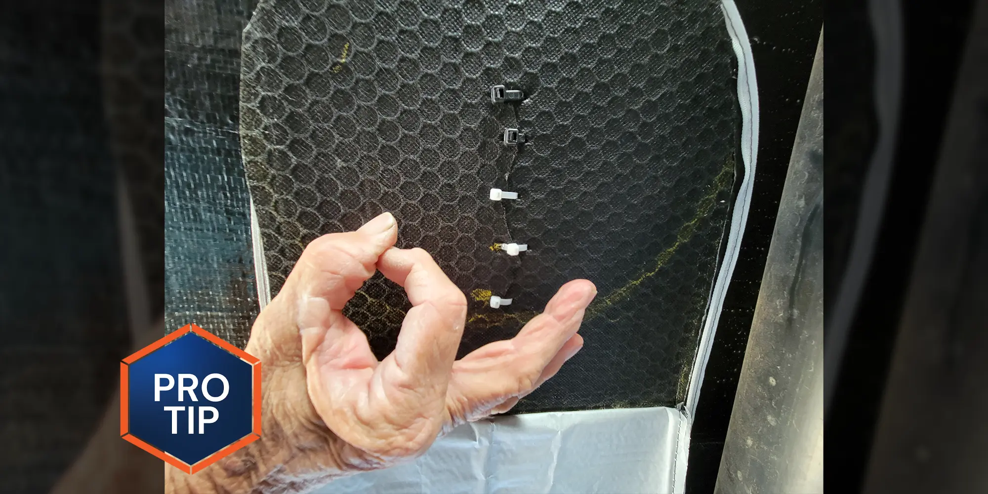 a hand makes the okay gesture in from of an area of Coroplast material being held together by a stitching of five zip ties