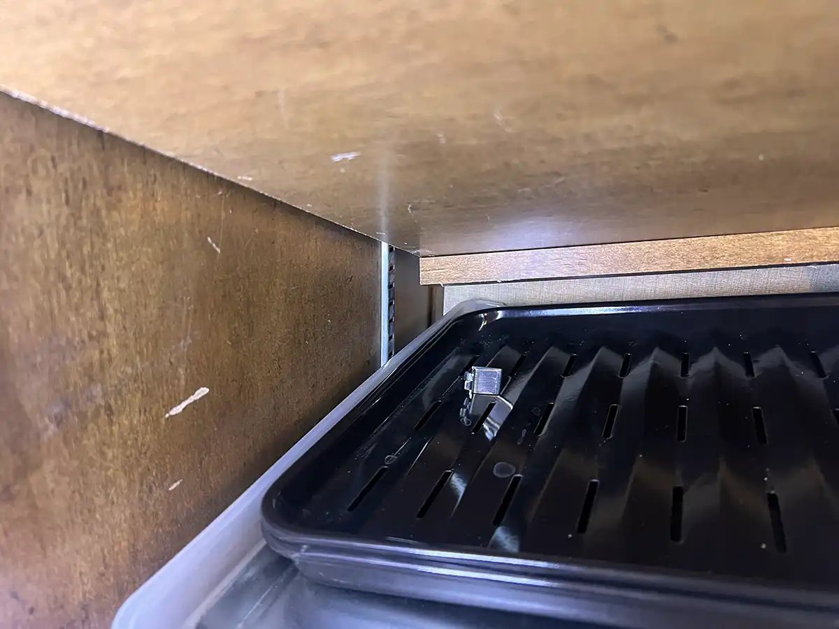 close view under a slightly fallen pantry shelf showing a strewn clip