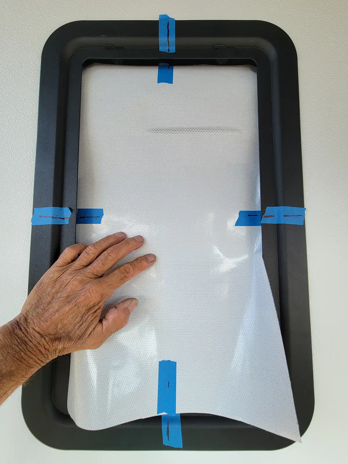 the vinyl is placed on the window and lined up with the marks on the blue painter’s tape guides