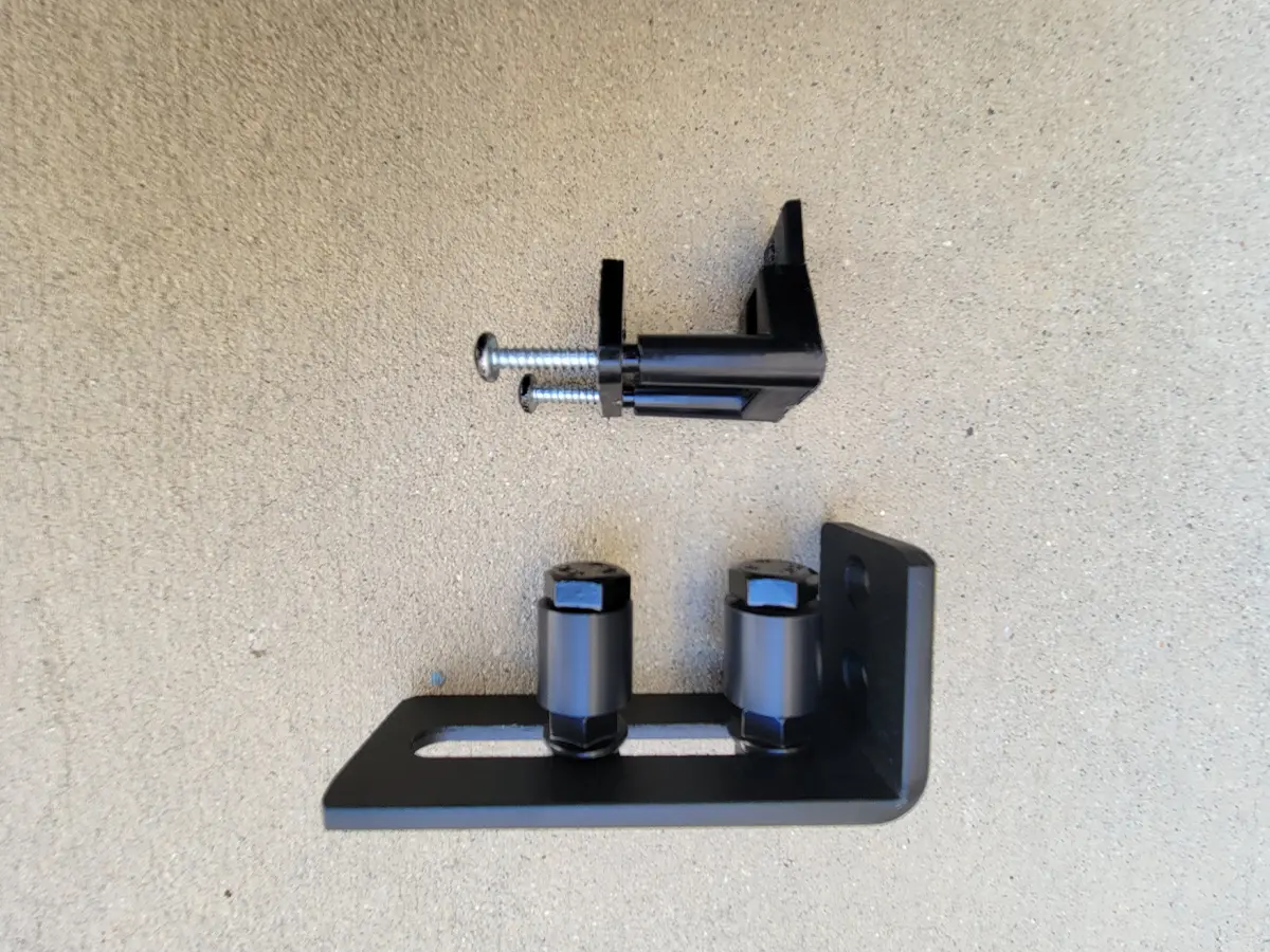 the original thin plastic sliding-door guide (top) and the barn door roller bracket (bottom)