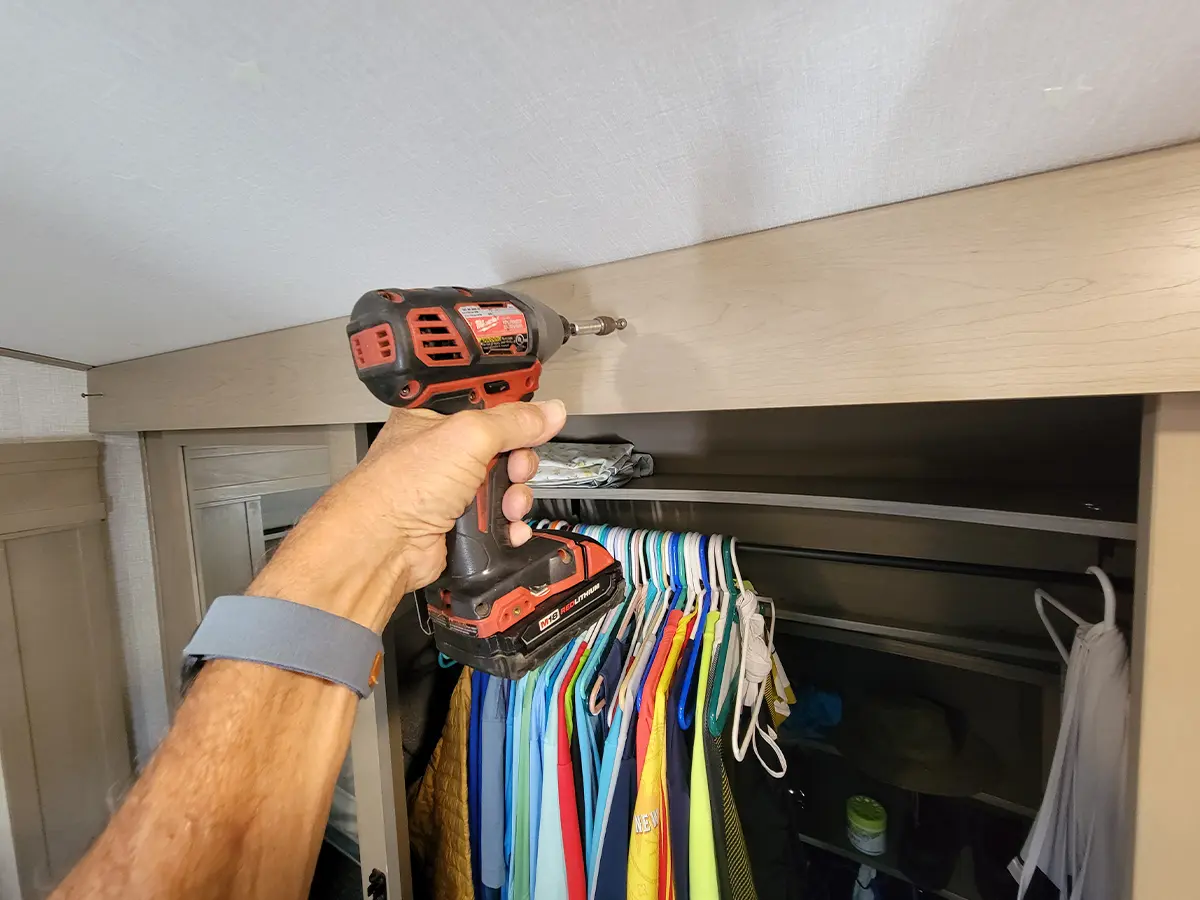 a drill gun is used to remove the screws holding the wardrobe closet header board in place