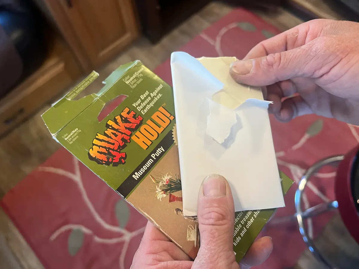 hands hold an open package of Quake Hold Museum Putty