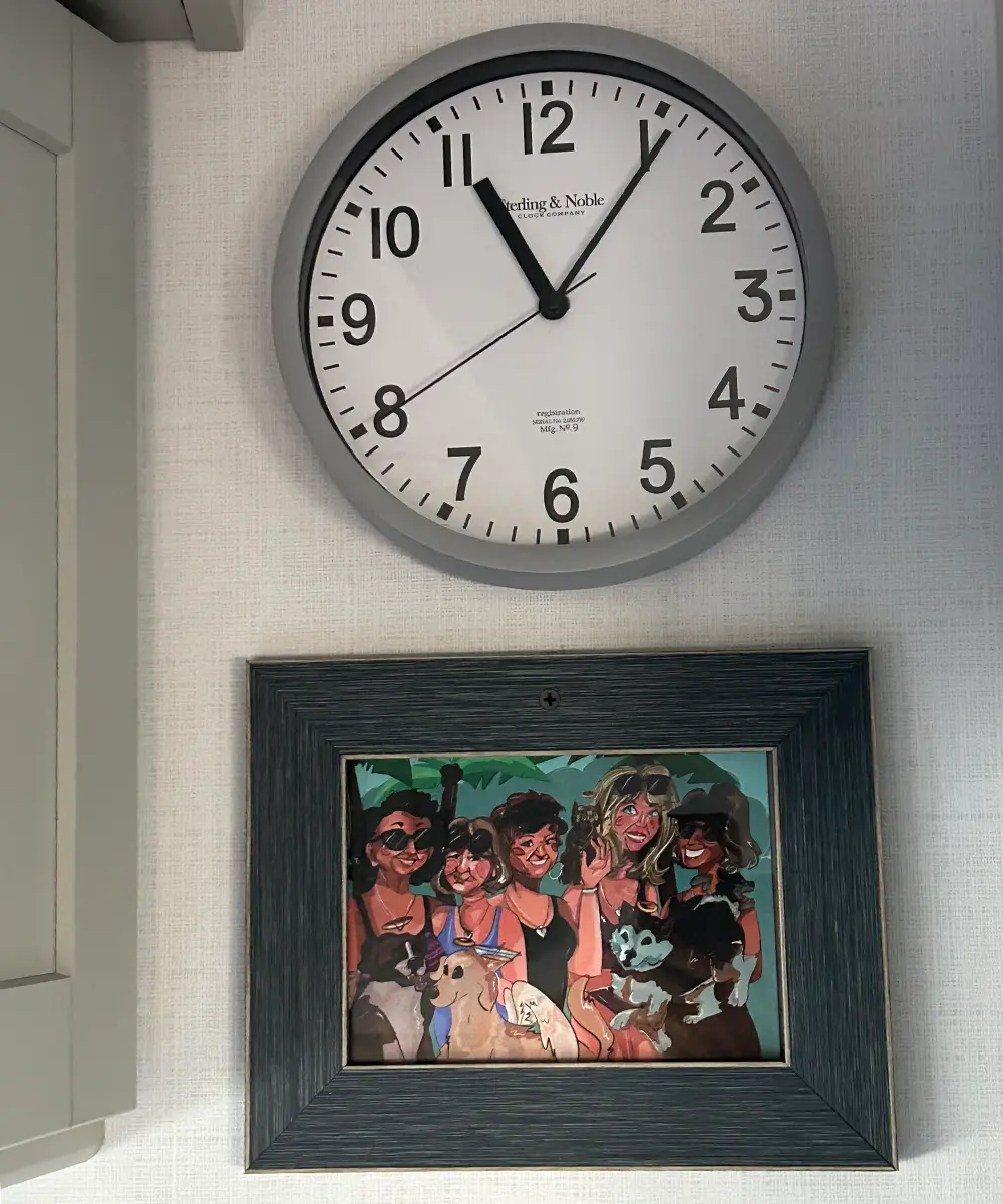 a clock and a framed illustration of a group of women friends hang from an RV wall