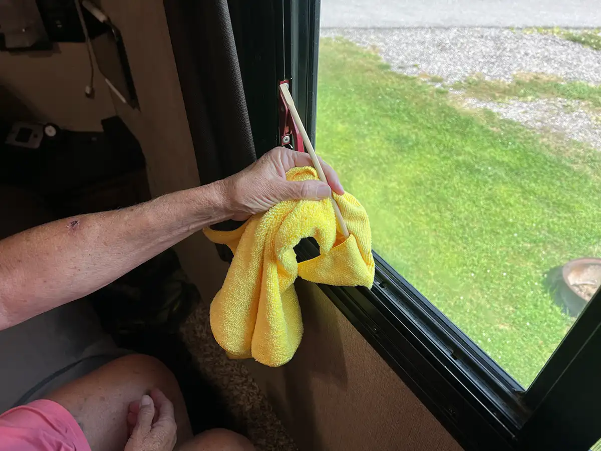 a bamboo chopstick wrapped in a microfiber towel is used to clean an RV window track