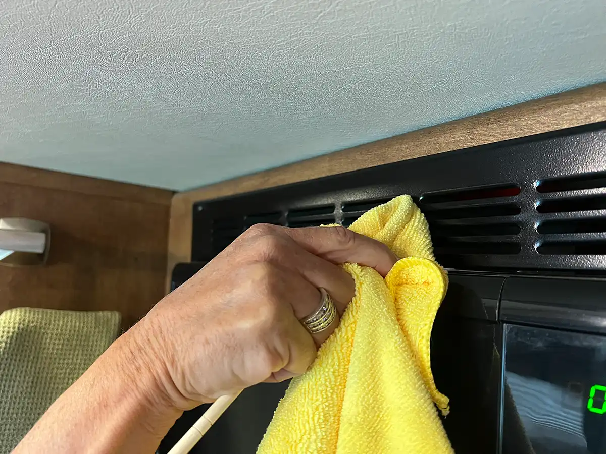 a bamboo chopstick wrapped in a microfiber towel is used to clean the vents of the galley microwave