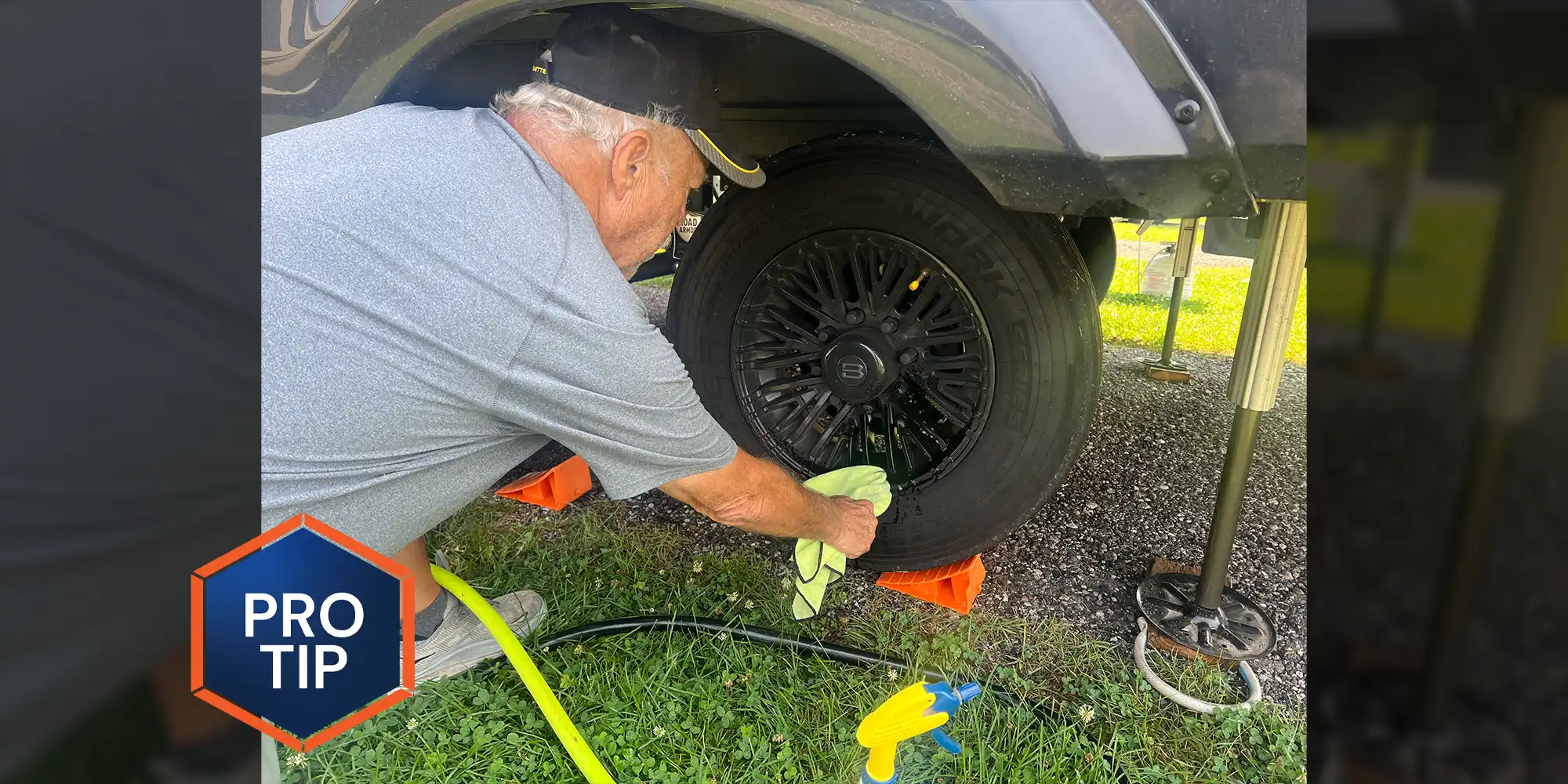 a man kneels beside the front rim of a large vehicle, he uses a microfiber towel to clean between the spokes of the rim